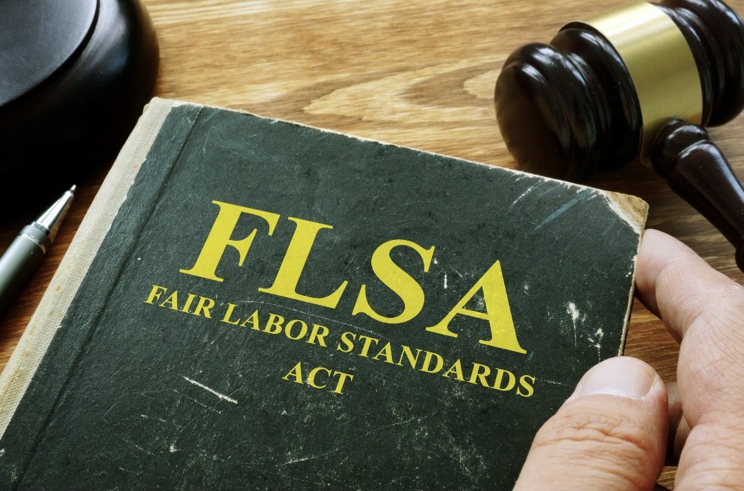Green book with FLSA Fair Labor Standards Act in yellow on a desk with a gavel